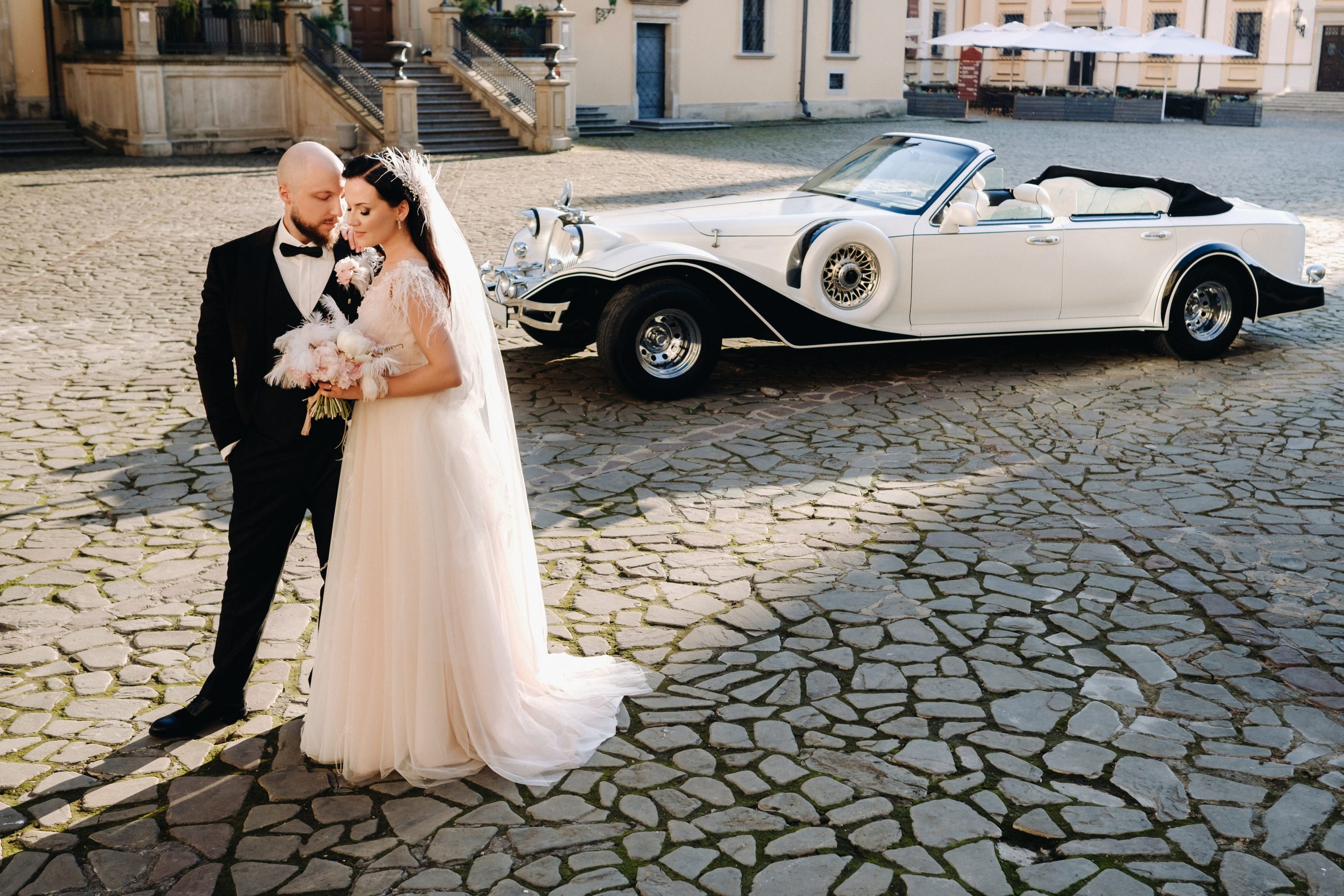 Elegant wedding couple In the courtyard of the castle near a retro car.