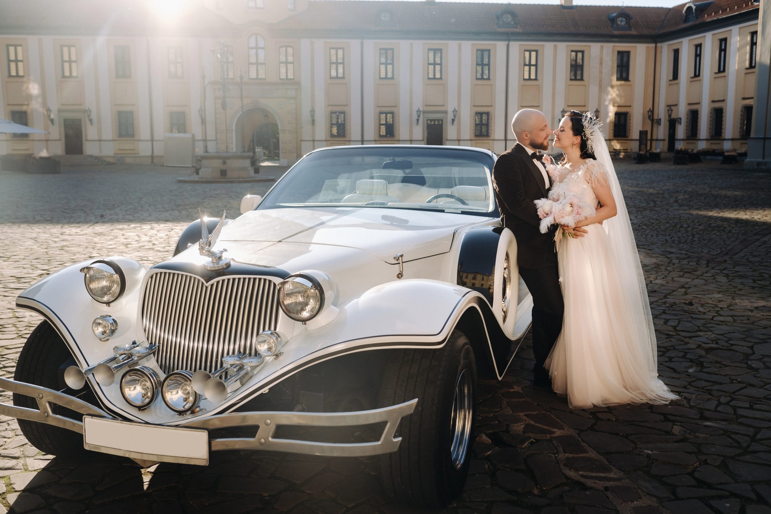 Elegant wedding couple In the courtyard of the castle near a retro car.