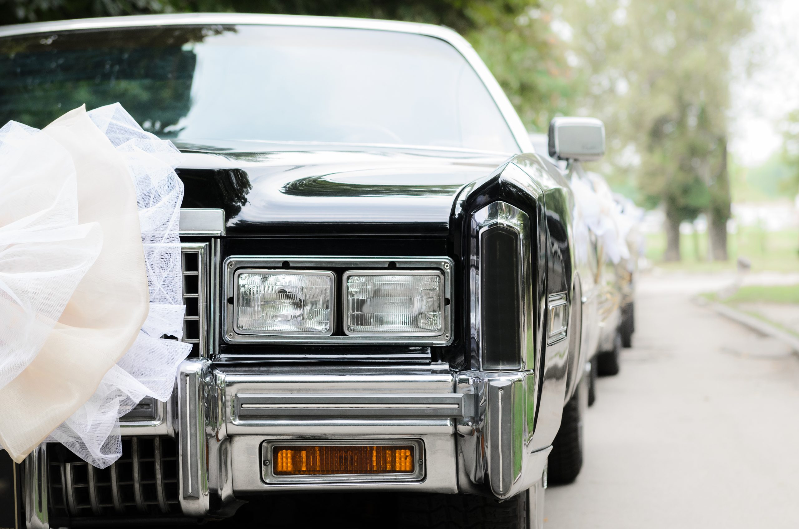 black vintage wedding car with white bow